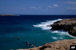 Jenazah migran dari kapal karam terlihat beberapa hari setelahnya di teluk berbatu di pulau Kythira, Yunani selatan, Jumat, 7 Oktober 2022. (Foto: AP)