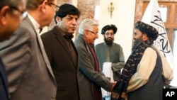 Mullah Abdul Ghani Baradar, the Taliban-appointed deputy prime minister for economic affairs, right, shakes hands with Pakistan's defense minister, Khawaja Mohammad Asif, during a meeting in Kabul, Afghanistan, Feb. 22, 2023.