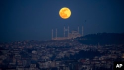 FILE - A full moon rises behind the Camlica mosque in Istanbul, Turkey, Feb. 24, 2024. 