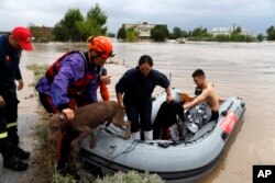 Firefighters with a rubber dinghy evacuee people and dogs from flooded buildings in Larissa, central Greece, Sept. 6, 2023.