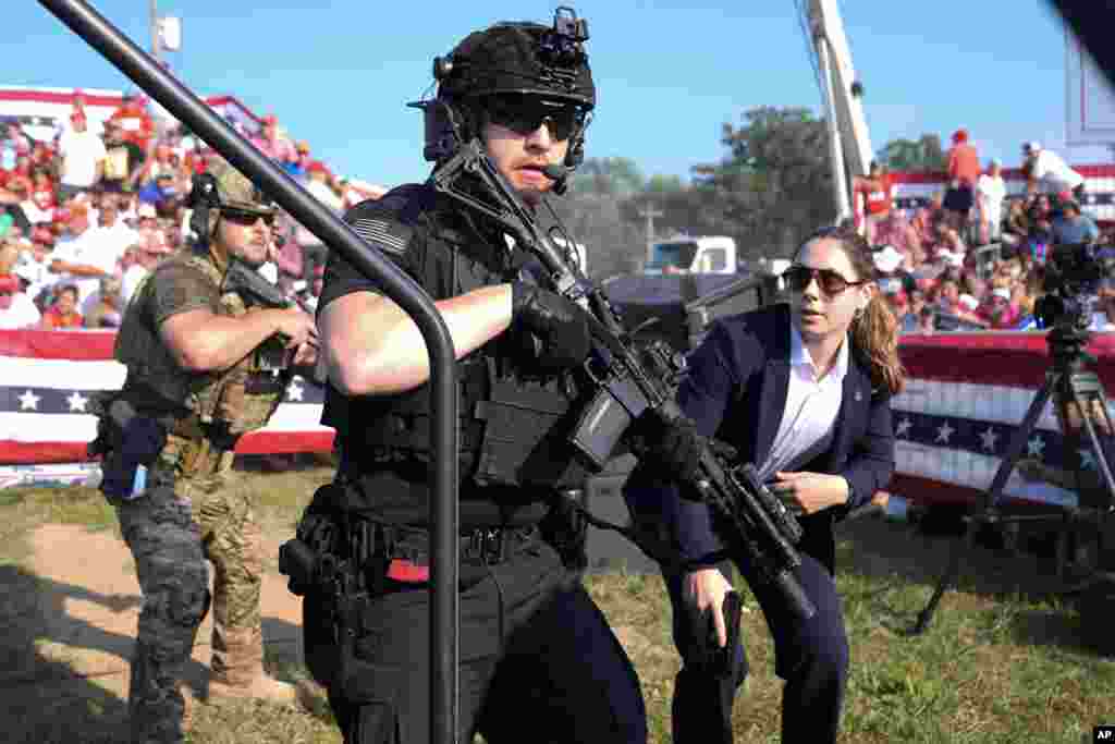 U.S. Secret Service agents respond President Donald Trump is surrounded on stage by other agents.