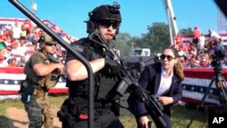 U.S. Secret Service agents respond as Republican presidential candidate former President Donald Trump is surrounded on stage by U.S. Secret Service agents at a campaign rally, July 13, 2024, in Butler, Pennsylvania.