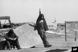 FILE - American Indian Movement members stand guard at a roadblock on a route into Wounded Knee, S.D., March 19, 1973, as talks between U.S. government representatives and American Indian Movement leaders continue.