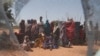 FILE - Somali refugees are seen through a discarded mosquito net as they gather in the new arrivals area of the Dadaab refugee camp near the Kenya-Somalia border, in Garissa county, Kenya, Jan. 17, 2023.