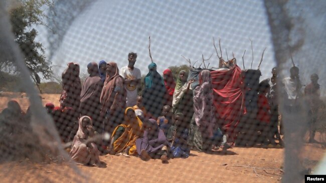 FILE - Somali refugees are seen through a discarded mosquito net as they gather in the new arrivals area of the Dadaab refugee camp near the Kenya-Somalia border, in Garissa county, Kenya, Jan. 17, 2023.