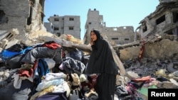 A Palestinian woman inspects the damage after Israeli forces withdrew from Shejaiya neighborhood following a ground operation, amid the Israel-Hamas conflict, in eastern part of Gaza City, July 10, 2024.