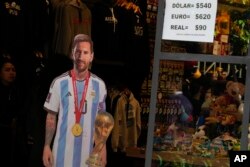 Sebuah toko memajang di selembar kertas nilai tukar mata uang tidak resmi di sebelah potongan Lionel Messi seukuran aslinya, di Buenos Aires, Argentina, Rabu, 26 April 2023. (AP/Natacha Pisarenko)