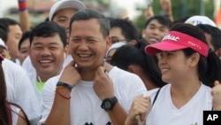 Lt. Gen. Hun Manet, center, of the Royal Cambodian Armed Forces (RCAF) and the first son of Cambodian Prime Minister Hun Sen, smiles before the start of the international half-marathon in front of Royal Palace in Phnom Penh, Cambodia, June 12, 2016.
