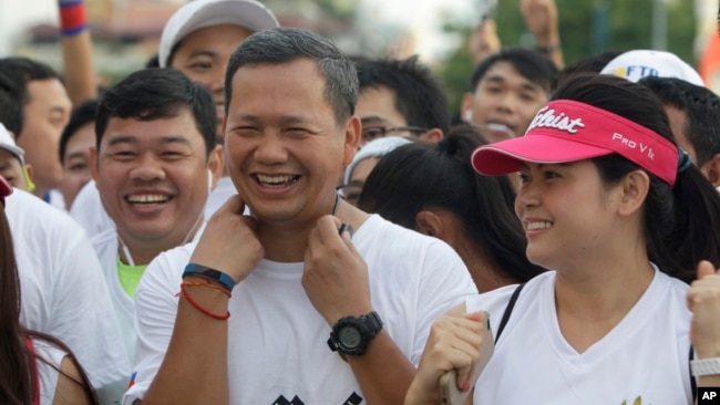 Lt. Gen. Hun Manet, center, of the Royal Cambodian Armed Forces (RCAF) and the first son of Cambodian Prime Minister Hun Sen, smiles before the start of the international half-marathon in front of Royal Palace in Phnom Penh, Cambodia, June 12, 2016.