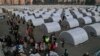 People who lost their houses in the devastating earthquake, lineup to receive food at a makeshift camp, in Iskenderun city, southern Turkey, Feb. 14, 2023. 