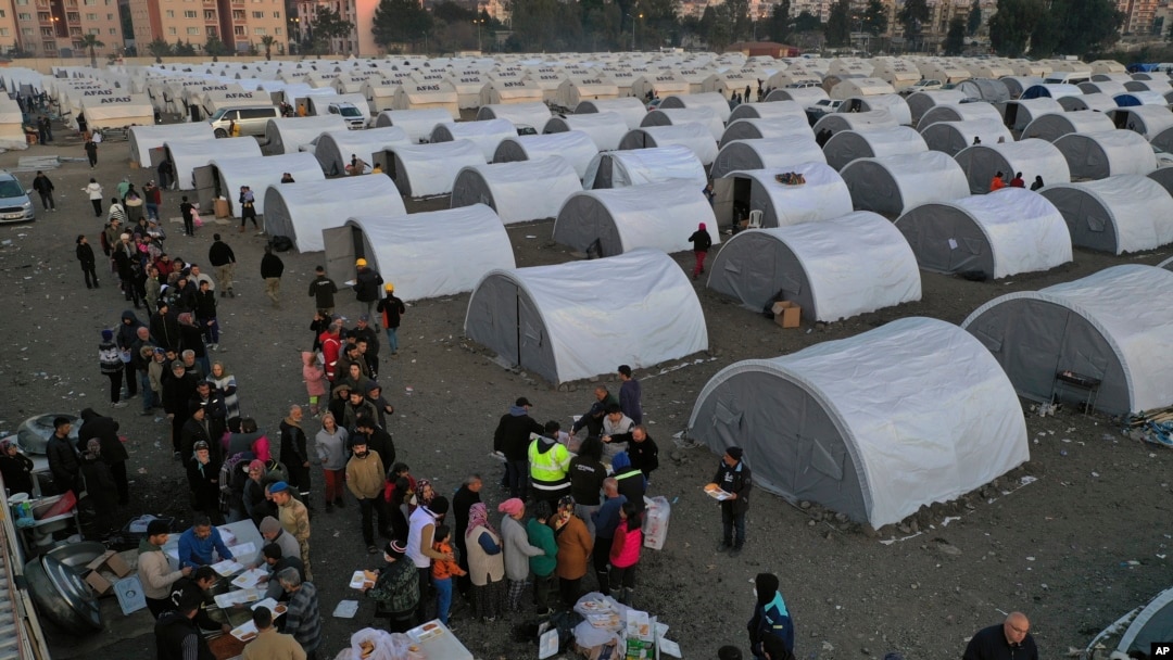 People who lost their houses in the devastating earthquake, lineup to receive food at a makeshift camp, in Iskenderun city, southern Turkey, Feb. 14, 2023. 
