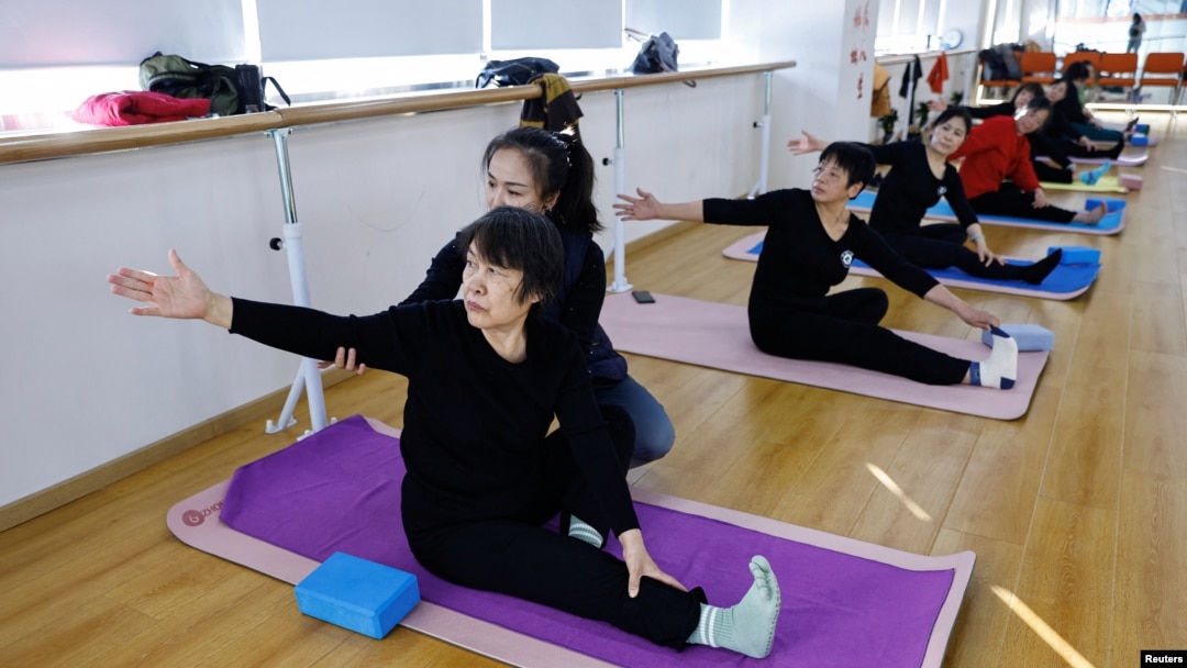 Seorang instruktur melatih para lansia gerakan yoga dalam kelas yoga di Mama Sunset, sebuah pusat pelatihan untuk para lansia di China, di Beijing, pada 15 Januari 2024. (Foto: Reuters/Tingshu Wang)