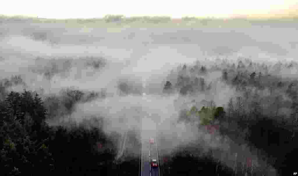 Foto udara menunjukkan beberapa kendaraan melaju di jalan pada pagi hari yang berkabut, di Wehrheim dekat Frankfurt, Jerman.