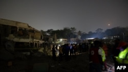 Des personnes se tiennent sur le site d'une explosion dans la région de Bodija à Ibadan le 16 janvier 2024.