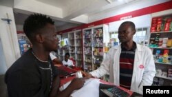 FILE —Sodiq Ajibade, 29, who suffers from bouts of asthma attacks, speaks to a pharmacist about his medication at a pharmacy in Lagos, Nigeria December 11, 2023. 