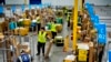 FILE - Amazon employees load packages onto carts before they are transferred to trucks for distribution, at an Amazon facility in South Gate, California, July 16, 2024.