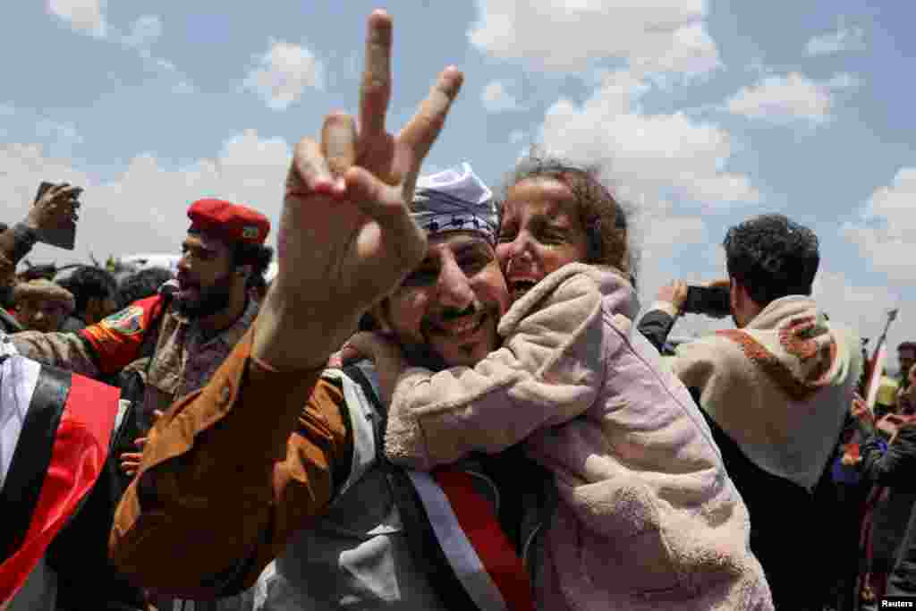 Seorang tahanan yang dibebaskan, memberi isyarat dengan dua jarinya sambil menggendong seorang anak, setibanya di Bandara Sanaa dengan pesawat sewaan Komite Palang Merah Internasional (ICRC), di tengah pertukaran tahanan antara dua pihak dalam konflik Yaman, di Sanaa, Yaman.