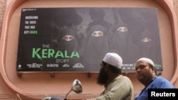 Pengendara motor melintas di depan poster film "The Kerala Story" yang terpampang di luar bioskop di Mumbai, India, 9 Mei 2023. (Foto: Francis Mascarenhas/Reuters)