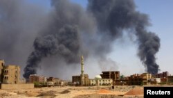 A man walks while smoke rises above buildings after aerial bombardment, during clashes between the paramilitary Rapid Support Forces and the army in Khartoum North, Sudan, May 1, 2023.