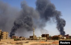 Seorang pria berjalan di tengah asap membubung di atas bangunan setelah serangan udara, saat berlangsungnya bentrokan antara Pasukan Dukungan Cepat paramiliter dan tentara di Khartoum Utara, Sudan, 1 Mei 2023. (REUTERS/Mohamed Nureldin Abdallah)