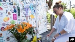 Meagan Bryon of Hoboken, New Jersey, places a 'lost shaker of salt' at an impromptu memorial for Jimmy Buffett outside the Shrimpboat Sound recording studio, Sept. 2, 2023, in Key West, Florida. (Rob O'Neal/Florida Keys News Bureau via AP)