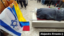 Banderas de Israel y Colombia pueden verse el 12 de octubre de 2023 frente a los restos de la colombiana Ivonne Rubio, muerta tras el ataque de Hamás al festival Nova, al comienzo de la incursión del grupo militante a territorios israelíes cercanos a la Franja de Gaza. 