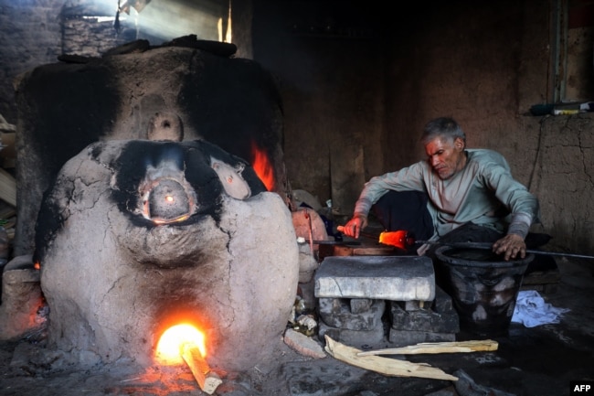 FILE - In this Aug. 11, 2024, photo, Ghulam Sakhi Saifi, an Afghan glassblower, crafts glassware at his traditional workshop in Afghanistan's western city of Herat.