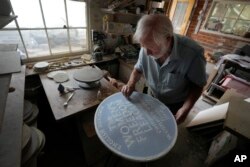 Ned Heywood fettling the glaze on the clay plaque during the making of an English Heritage Blue Plaque, at Heritage Ceramics, The Workshop Gallery in Chepstow, Wales, Sept. 6, 2023.