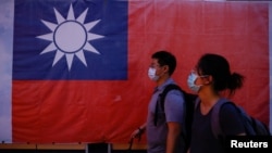 台北街头民众走过竖立的台湾旗帜。（2023年8月18日）