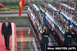 Presiden Joko Widodo memeriksa pengawal kehormatan saat upacara penyambutan di Istana Kepresidenan di Hanoi pada 12 Januari 2024. (Foto: AFP/Nhac NGUYEN)