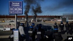 FILE: Dock workers face riot police as they stand in front of a burning barricade next the port of Marseille southern France, Wednesday, March 22, 2023. With the Constitutional Council's approval of most of the pension reforms, unrest may continue. 