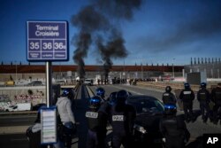 Pekerja dermaga berhadapan dengan polisi anti huru hara saat mereka berdiri di depan barikade yang terbakar di dekat pelabuhan Marseille, Prancis selatan, Rabu, 22 Maret 2023. (AP/Daniel Cole)