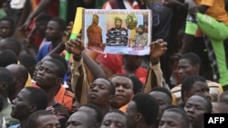 FILE - A man holds a placard with the image of Niger's new military ruler General Abdourahamane Tiani on as people protest outside the Niger and French airbase in Niamey on Sept. 2, 2023 to demand the departure of the French army from Niger.