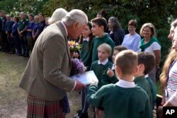 Britain's King Charles III and Queen Camilla receive flowers and a card from local school children as they leave Crathie Parish Church after a service to mark the first anniversary of the death of Queen Elizabeth II, near Balmoral, Scotland, on Sept. 8, 2023.