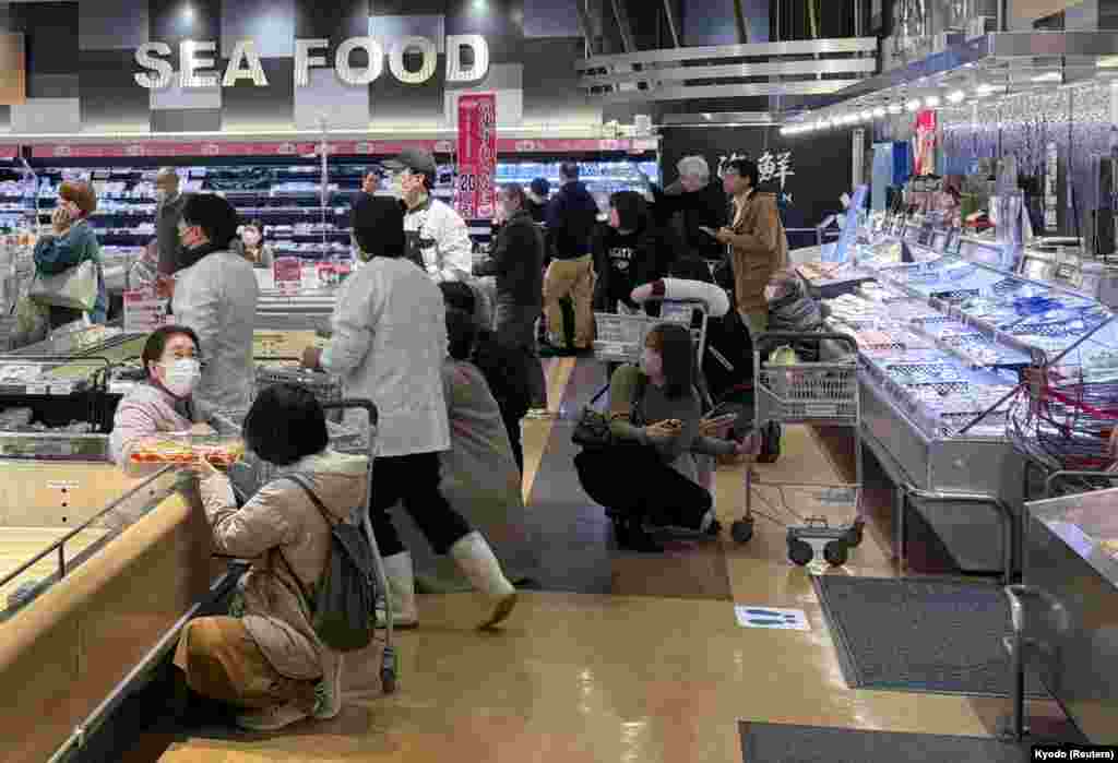 Shoppers crouch down as an earthquake hit the region at a supermarket in Toyama, Japan, in this photo released by Kyodo.