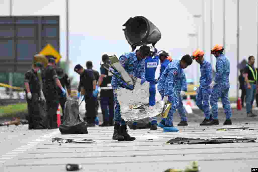 Members of the Special Disaster and Emergency Response team collect debris at the crash site in Shah Alam a day after a light plane crashed in Malaysia's central Selangor state.