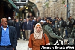 Una mujer musulmana camina por la ciudad Vieja de Jerusalén, fuertemente custodiada por policías israelíes durante el primer viernes del mes sagrado del Ramadán.