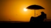 Arhiva - Čovek se odmara ispod suncobrana tokom zalaska Sunca, u Njuport Biču, Kalifornija.