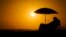 FILE - A person rests under an umbrella as the sun sets, Sept. 12, 2023, in Newport Beach, Calif. 