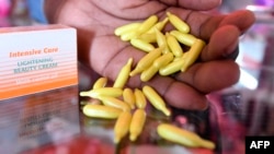 A beautician displays capsules and cream used for skin lightening at a beauty shop, in Nairobi, Kenya, on July 6, 2018.