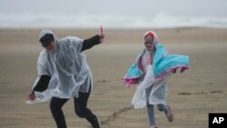 Beach combers run along the beach on Feb. 24, 2023, in Huntington Beach, California, during a winter storm that pounded the U.S.