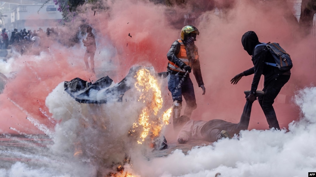 Sebuah tabung gas air mata meledak saat para pengunjuk rasa mencoba membantu rekan mereka yang terluka di luar Parlemen Kenya selama aksi pemogokan nasional untuk memprotes kenaikan pajak dan RUU keuangan 2024, di ibu kota Nairobi. (AFP) 