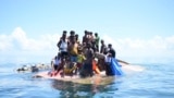 Rohingya refugees stand on their capsized boat before being rescued in the waters off West Aceh, Indonesia, March 21, 2024. 