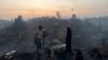 A Rohingya refugee family stands near their shelter that has been destroyed after a fire broke out in the Rohingya refugee camp in Balukhali in Cox's Bazar, Bangladesh, March 5, 2023. 