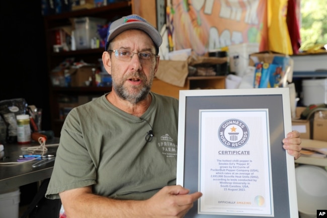 Ed Currie holds up his certification that his new Pepper X variety of peppers is the hottest in the world according to the Guinness Book of World Records on Tuesday, Oct. 10, 2023, in Fort Mill, S.C. (AP Photo/Jeffrey Collins)