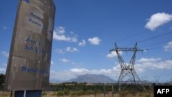 FILE: A dilapidated sign for Eskom, the South African electricity authority, stands next to electricity pylons and Table Mountain in the distance near Cape Town on January 22, 2023. 
