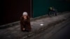 A woman kneels as the funeral procession with the body of Kostiantyn Kostiuk passes by during his funeral in Borova, near Kyiv, Ukraine, Feb. 18, 2023