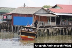 Seorang perempuan sedang turun dari sampan yang merupakan transportasi air di Kampung Nelayan Seberang, Kota Medan, Sumatra Utara. (VOA/Anugrah Andriansyah)