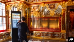 FILE - A woman shoots a photo in front of empty display cases after the 2019 theft in the Jewel Room, during the reopening of the Green Vault Museum in Dresden's Royal Palace of the Dresden State Art Collections (SKD) in Dresden, Germany, May 30, 2020.