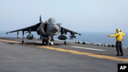 FILE - A US sailor on the amphibious assault ship USS Bataan directs a Marine Corps AV-8B Harrier II jet in the Gulf of Oman.